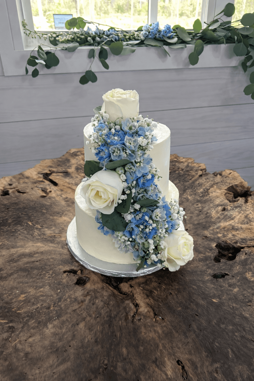 Two-tier white wedding cake with blue flowers